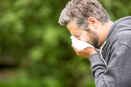 allergien Mann niest in Taschentuch